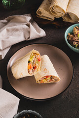 Shawarma in pita bread with meat and vegetables on a plate on the table vertical view