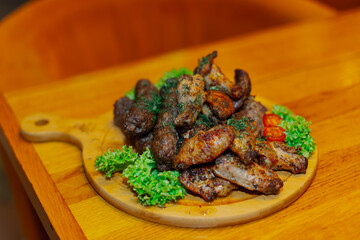 Fried wings, fried sausages and grilled meat all on one wooden tray with vegetables