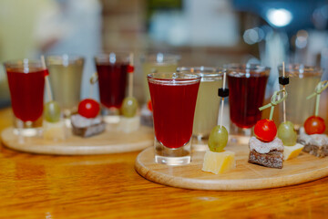 Alcoholic liqueur in shots of different types with a snack on a wooden stand on a bar counter in a restaurant. liqueur set. close-up