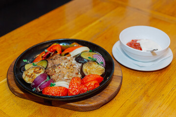 A variety of baked vegetables along with fried pork in a pan with sauce