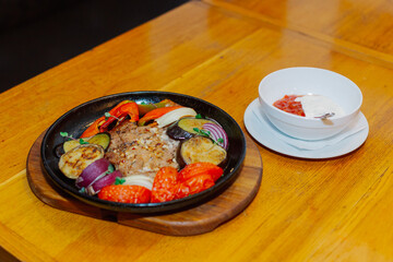A variety of baked vegetables along with fried pork in a pan with sauce. Beautiful feeding to the restaurant