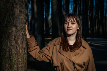 Young woman smiling in sunlit pine forest in autumn
Description: A young woman with brown hair and...