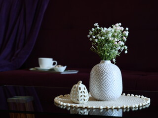 A white vase with flowers sits on a coffee table in a stylish living room, enhancing ambiance