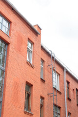 The facade of the old red brick building that was built 100 years ago against the backdrop of the White Sky. Ancient decoration of the building. Restoration of buildings