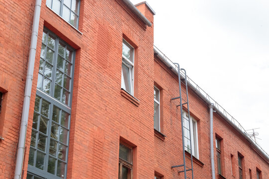 The facade of the old red brick building that was built 100 years ago against the backdrop of the White Sky. Ancient decoration of the building. Restoration of buildings. Old details