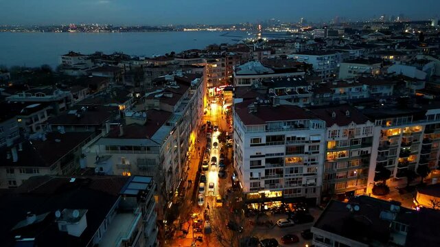 A drone flies over a glowing street in the evening in the Moda district of Kadikoy, Istanbul, Turkey
