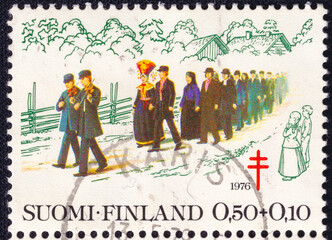 Finnish postage stamp from 1976 featuring a traditional rural wedding procession with musicians and...