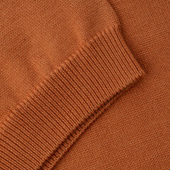 Elastic band close up on the sleeve of a terracotta orange knitted cotton polo t-shirt