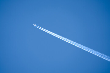 a twin engined jet liner aircraft in deep blue sky, contrails vapour trails