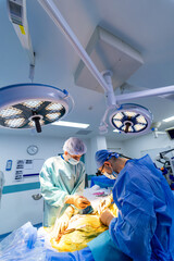 Surgeons at modern facility. Two surgeons dressed in scrubs are conducting a surgical procedure in...