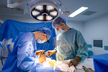 Surgeons in delicate surgery. Two surgeons in scrubs and masks collaborate in a brightly lit operating room on a surgical procedure.
