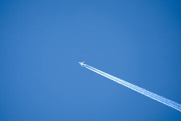 a twin engined jet liner aircraft in deep blue sky, contrails vapour trails