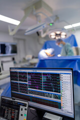 Surgeons in the OR. Surgeons in scrubs focus on a patient during surgery, while monitors display...