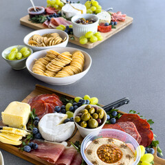 Top view of a gourmet charcuterie board or cheese platter with various meats, fruits and cheese on a wooden board