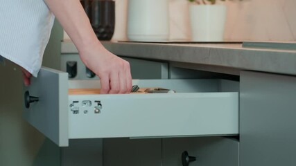 Person opens a kitchen drawer with various utensils in wooden cutlery tray. Woman opening kitchen cabinet. Concept of home organization and functionality interior
