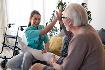 Fototapeta premium Smiling Caucasian Nurse Helping Elderly Male Patient with Anti-Thrombosis Stockings Indoors