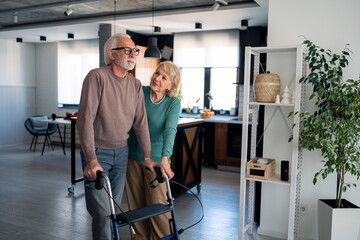 Compassionate Caucasian Woman Assisting Husband with Walker in Well-Lit Contemporary Living Space