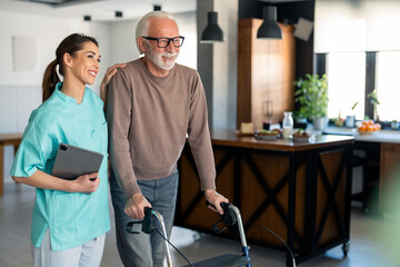 Supportive Female Physiotherapist Assisting Elderly Male Patient with Walker in Bright Indoor...
