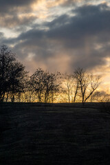 Landscape photo with beautiful sunset and clouds on the sky , field and trees , spring evening in the woodlands ,sun lights , beautiful nature 