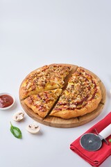 Baked sliced ​​pizza on yeast dough with chicken fillet, mozzarella cheese and mushrooms on a wooden board on a white background. Unsweetened baking. Italian cuisine.