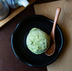 Sweet tasty green tea flovored ice-cream, served with wooden spoon on black cup