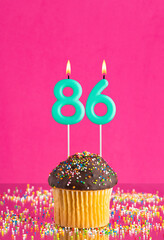 Birthday cupcake with number 86 candle - Celebration card on fuchsia background