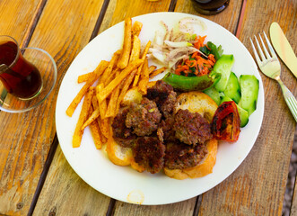 Delicious turkish kofte and French fries on a wooden board