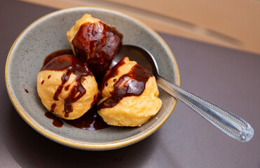 Appetizing profiteroles with filling of pastry cream served with dark chocolate ganache