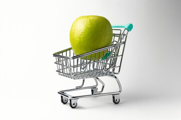 Green apple sitting in miniature shopping cart on white background