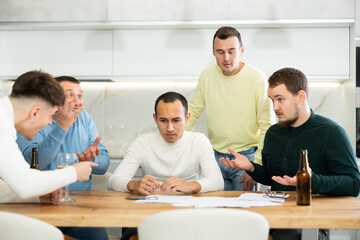 Brainstorming - male friends drinking beer and trying to solve financial problems by consulting each other while sitting at the table