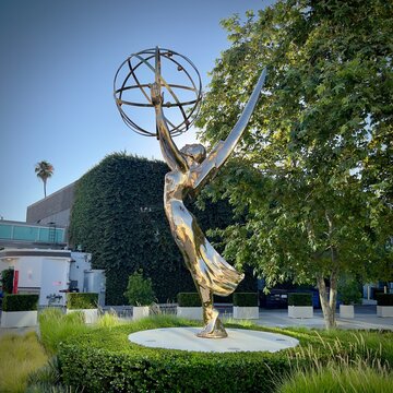 NORTH HOLLYWOOD, CA, JUL 31, 2024: close view of gleaming Emmy statue with its distinctive atom-like sphere held aloft by a winged figure, set against greenery and blue sky