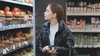 Shopper browsing produce section, picking colorful fruits and vegetables, representing healthy eating and wellness focused grocery shopping