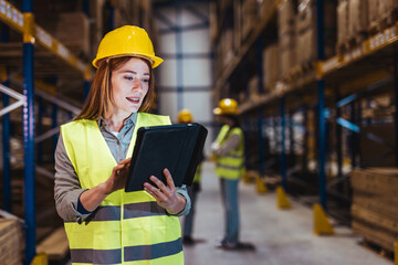 Worker Inspecting Tablet in Warehouse with Safety Gear