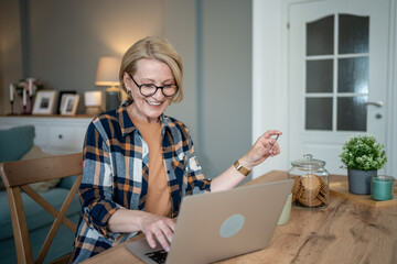 Senior woman working remotely and enjoying cookies at home