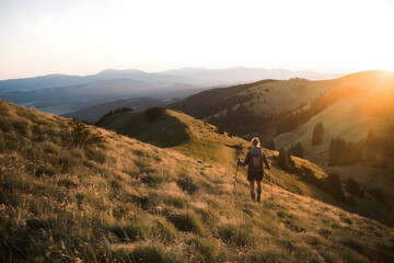 Hiker walking uphill in a golden sunset over rolling hills