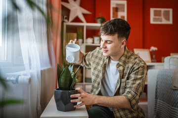 young man take care of home plant use watering can, gardening concept
