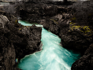 Barnafoss is a stunning Icelandic waterfall with turquoise water rushing through a narrow lava canyon. Its name, 