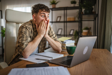 angry and shocked young man look at laptop screen while study at home