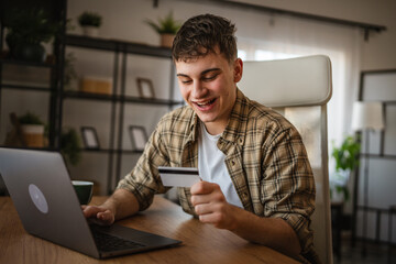 Fototapeta premium young man enjoy at online shopping use credit card and laptop at home