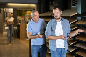 Hardware store salesperson advises an elderly customer on buying the best laminate flooring