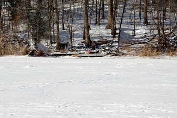 Winter cottage country scene looking toward dock over frozen lake in winter forest scene