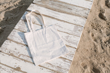 White linen tote cotton, mesh bag on beach chair, sand background. Zero waste, no plastic, eco friendly shopping, recycling concept. Blank mockup shopper, place for art logo text. Flat lay copy space.