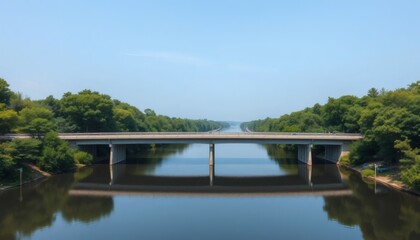 Fototapeta premium Bridge Over Calm River Reflecting Trees and Blue Sky on a Sunny Day