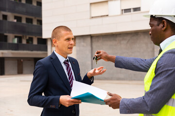 Commissioning of the new shopping center - businessman and builder exchange keys and documents
