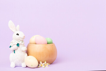 Easter bunny with painted eggs on color background