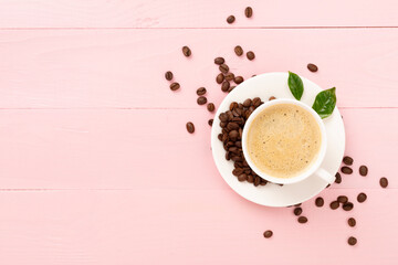 Cup of coffee with coffee beans and leaves on wooden background,top view