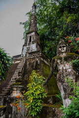 Ancient Stone Stupa and Weathered Buddha Sculpture Surrounded by Lush Greenery in Buddha Park,...