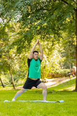 Young sportsman performs gymnastics on mat in urban city park. Sporty Japanese male is practicing...
