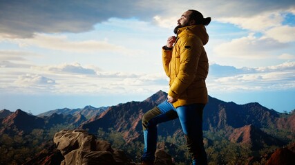 Determined traveler enjoys the solitude of a mountain summit, where the panoramic view represents...