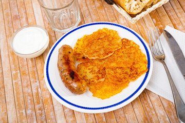Homemade fried vegetable potato fritters latkes with grilled sausage and white sauce